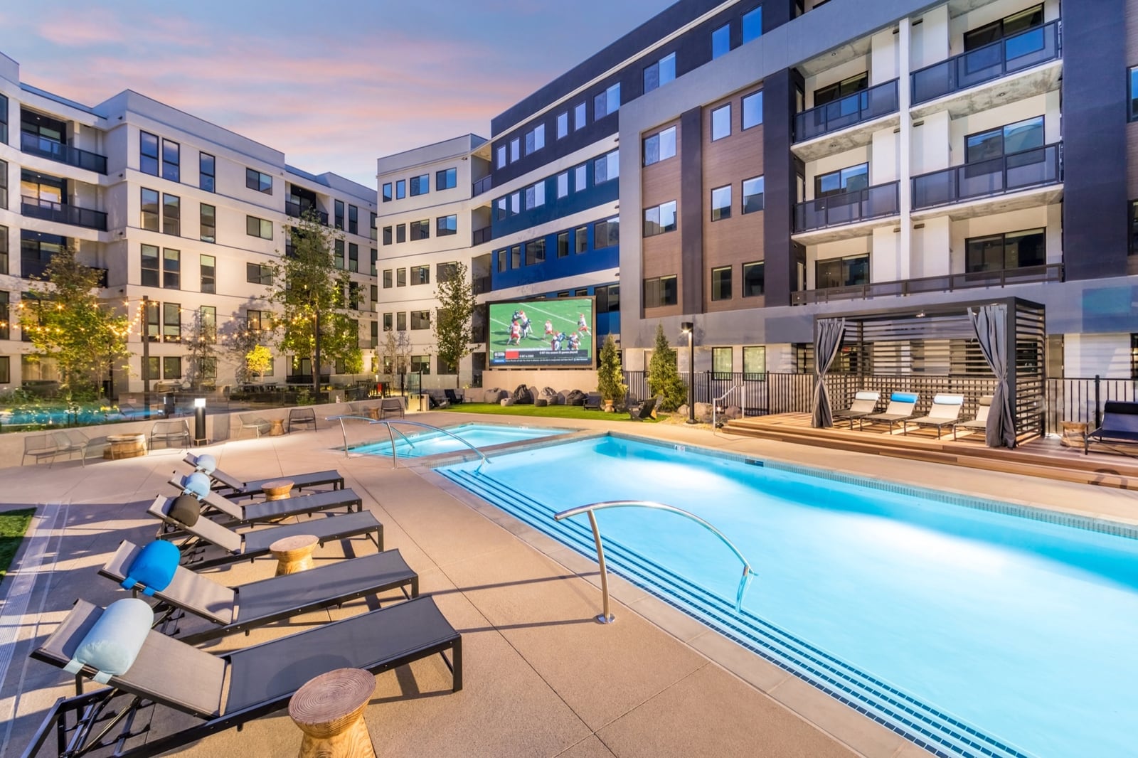 Pool and spa at dusk with poolside jumbo LED and private cabanas at Emory apartment homes